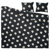 Llit ÖGONLOCKSMAL en color negre amb un estampat de flors blanques. El conjunt inclou una funda nòrdica i dos coixins, fets amb una barreja de cotó i viscosa.