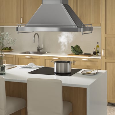 Cuina moderna amb campana inoxidable, llums led, bastidors penjants, placa d'inducció negra i armaris de fusta.