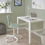 Escriptori i cadira per a nens blancs de PÅHL/ÖRFJÄLL. Disseny minimalista, paret verda, planta, llum, llapis.