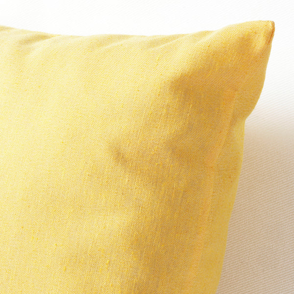 Un primer pla que mostra una funda de coixí groc daurat amb textura, destacant la seva qualitat i variacions naturals.