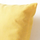 Un primer pla que mostra una funda de coixí groc daurat amb textura, destacant la seva qualitat i variacions naturals.