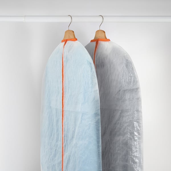 Dos vestits amb fundes protectores amb llaços taronges pengen perfectament en un armari.