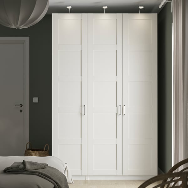Gran armari PAX blanc amb disseny elegant domina l'habitació, alt i ample, s'adapta perfectament al costat de la porta.