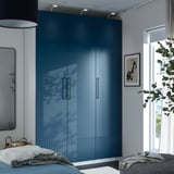 Armari PAX blau per finestra amb llum. Llit, mirall, planta a l'habitació minimalista.