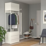 Armari modern blanc PLATSA amb roba, planta, cadira i porta.