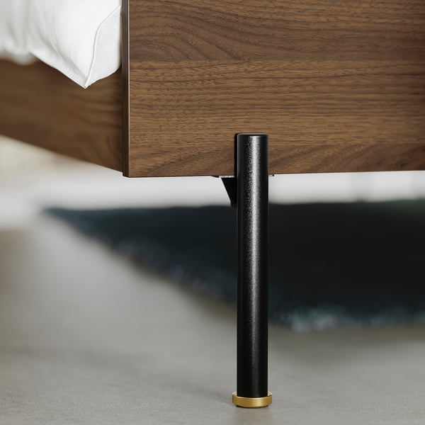 Marc de llit modern amb potes de metall negre elegant i detalls daurats, que mostren una artesania de qualitat.