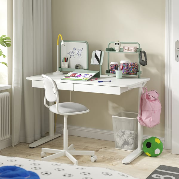 Escriptori blanc infantil amb calaixos, pissarra i espai de treball organitzat. Inclou cadira, ganxo de motxilla i emmagatzematge per a material escolar.