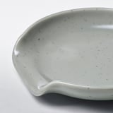 Cullera petita de gres gris clar amb un subtil patró tacat, dissenyada per evitar vessaments d'estris de cuina.