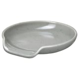 Un reposaculleres RÖDSYRA en blanc amb un patró de punts. Fabricat en gres, té una forma llisa i corba per facilitar l'emmagatzematge dels estris.