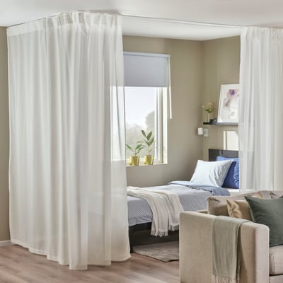 Dormitori modern amb cortines transparents, llit i test.