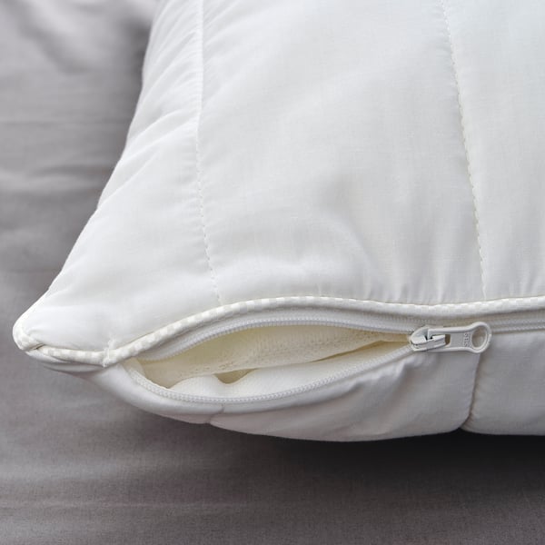 Primer pla d'un coixí blanc amb cremallera, que mostra costures d'alta qualitat i teixit suau.