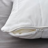 Primer pla d'un coixí blanc amb cremallera, que mostra costures d'alta qualitat i teixit suau.