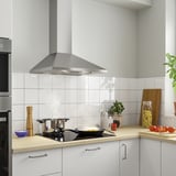 Cuina moderna amb campana d'acer inoxidable. Armaris blancs, taulells de fusta, articles de cuina.