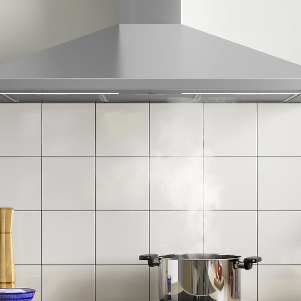 Campana d'acer inoxidable amb llum led sobre paret de rajoles, extractor a la vista.