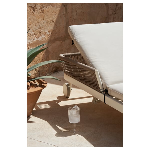 Moderna butaca d'exterior, coixí beix, vímet i blanc, respatller ajustable, al pati.