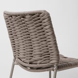 Cadira moderna de vímet amb teixit complex, feta de corda de polipropilè marró grisenc duradora. Un marc metàl·lic elegant, dissenyat per a ús exterior.