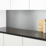 Taulell de cuina modern amb superfície negra elegant, backsplash gris clar, estris de fusta.