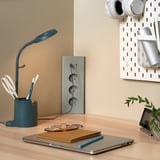Configuració ordenada de l'escriptori amb cable SKOTAT blau, ordinador portàtil, portàtil i planta.