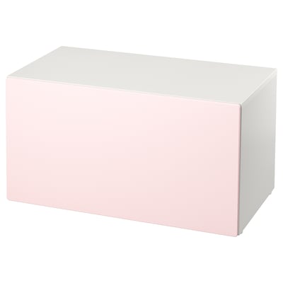 Un banc d'emmagatzematge smastad en rosa clar i blanc. Forma rectangular, disseny senzill, ideal per a l'emmagatzematge de joguines.