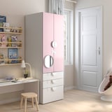 Habitació infantil amb armari rosa-blanc, prestatgeries, escriptori, llum i gronxador d'ós de peluix.