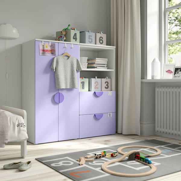 Habitació infantil amb emmagatzematge SMÅSTAD lavanda, que inclou armaris, prestatges i calaixos. Conjunt de tren de joguina compacte i estable sobre catifa.