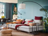 Acollidora sala d'estar amb parets de color verd verd, una chaise longue beix SÖDERHAMN, coixins de colors i plantes d'interior.
