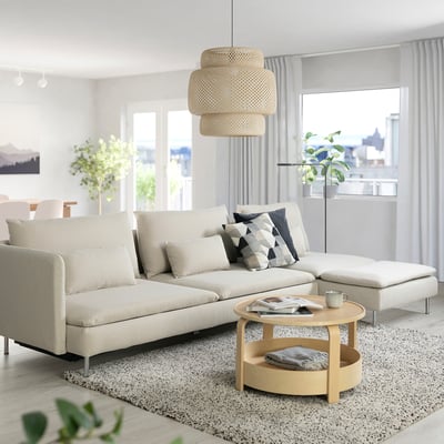 Sala d'estar moderna amb sofà-llit SÖDERHAMN gris, coixins, taula de centre i gran finestral.