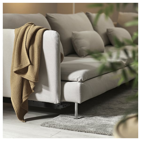 Sofà llit gris modern amb coixins, manta i potes metàl·liques. Perfecte per a una relaxació acollidora.