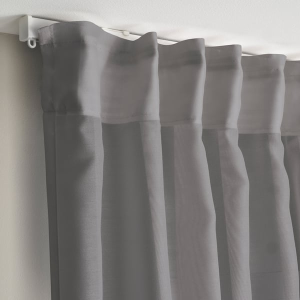 Les cortines grises transparents pengen amb plecs, difonent la llum solar per a la privadesa.
