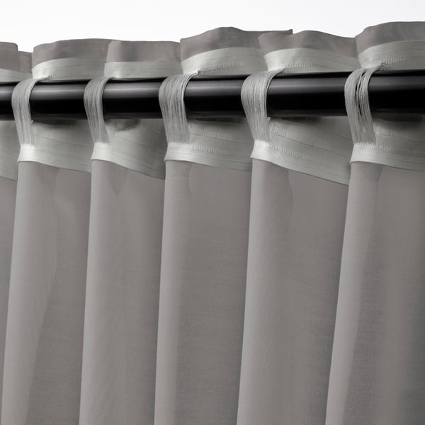 Cortines transparents STENFRÖ amb tapa d'ojal, amb teixit transparent per a la llum solar difusa i la privacitat. Color gris amb cinta adhesiva per facilitar el plisat.