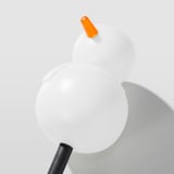 Llum en forma de ninot de neu amb globus blanc, nas taronja, base negra; llançar una brillantor brillant i acollidora.