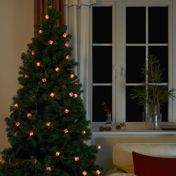 Un arbre de Nadal adornat amb llums de corda amb piles en forma de petits regals, creant un ambient festiu i càlid.