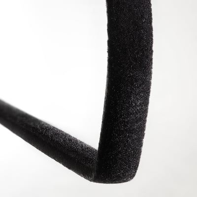 Tres penjadors minimalistes amb formes llises i corbes i ganxos, dissenyats per mantenir la roba al seu lloc sense deixar marques.