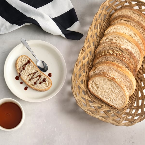 Cistella de pa de vímet amb pa tallat, drap i melmelada. Natural, càlid i acollidor.