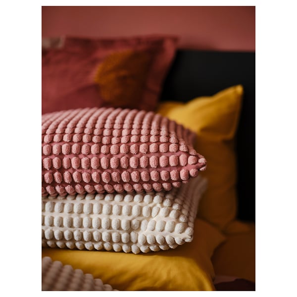 Coixins de textura rosa i blanca apilats; patrons suaus i rodons.