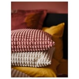 Coixins de textura rosa i blanca apilats; patrons suaus i rodons.