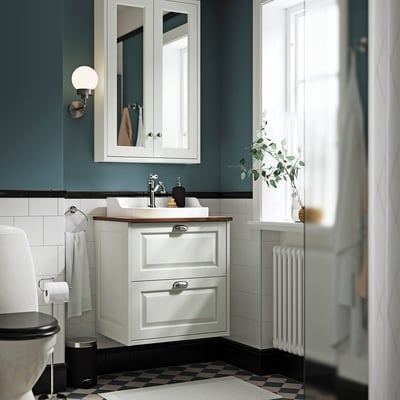 Tocador de paret TÄNNFORSEN, lavabo semi-encastat, terra en blanc i negre, radiador alt, parets verda verda, vegetació.