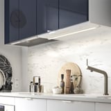Cuina moderna amb backsplash de marbre, aixeta inoxidable i campana de cuina elegant.