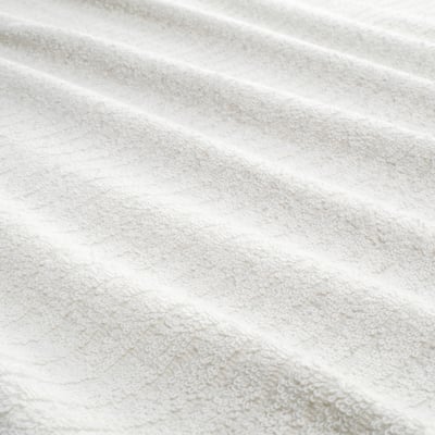 Una tovallola de cotó VÅGSJÖN blanca penja perfectament en un ganxo amb un estampat de ratlles i textura de pèl.