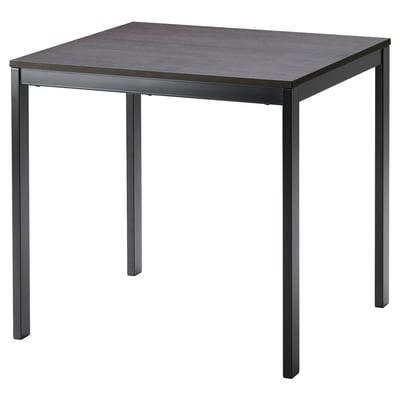 Una taula de menjador extensible VANGSTA en color negre amb tapa de fusta fosca, forma rectangular i potes metàl·liques resistents. Ideal per a seients espaiosos.