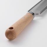 Ratllador d'acer inoxidable amb mànec de fusta i forat per penjar. O ratllador d'acer inoxidable resistent amb mànec de fusta i ganxo penjant.