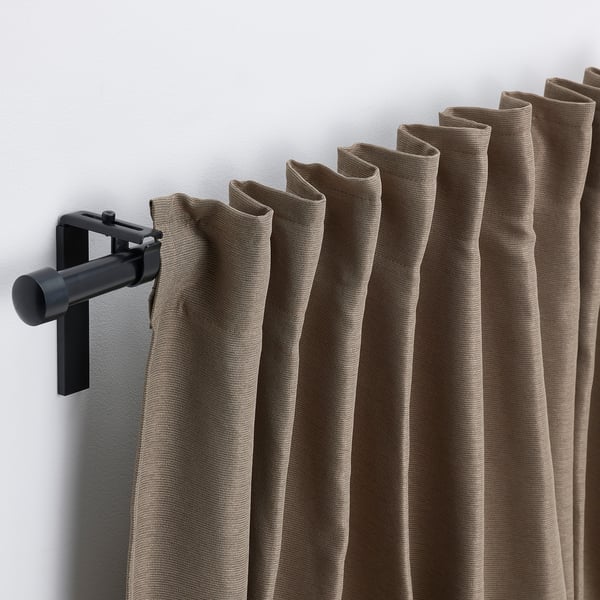 Les cortines marrons pengen perfectament de la vareta negra, oferint privadesa i control de la calor.