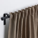 Les cortines marrons pengen perfectament de la vareta negra, oferint privadesa i control de la calor.