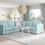 Sofà seccional VIMLE blau clar modern amb taula de centre de fusta clara, llum penjant elegant i grans finestrals.