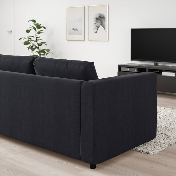 Sala d'estar moderna amb sofà negre VIMLE; TV de pantalla plana, decoració, planta; disseny minimalista i acollidor.