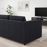 Sala d'estar moderna amb sofà negre VIMLE; TV de pantalla plana, decoració, planta; disseny minimalista i acollidor.