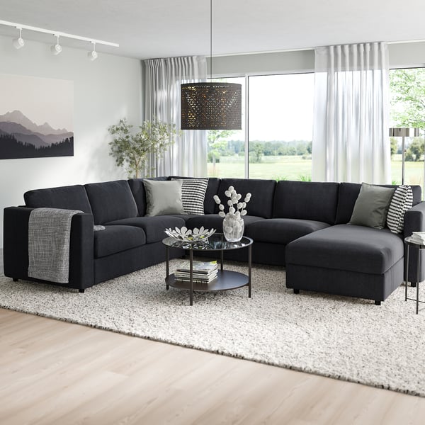 Sofà seccional VIMLE negre modern amb chaise, coixins grisos, grans finestrals, decoració de moda.