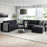 Sofà seccional VIMLE negre modern amb chaise, coixins grisos, grans finestrals, decoració de moda.