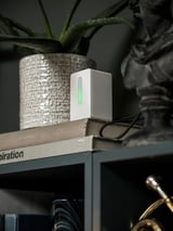 Un sensor de qualitat de l'aire blanc i elegant descansa sobre llibres apilats, mostrant llum verda.