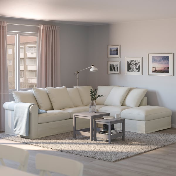 Sala d'estar moderna amb sofà crema, cortines rosa, taula de cafè i paret plena d'art.